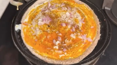 Crispy ghee karam onion egg dosa topped with onions and podi